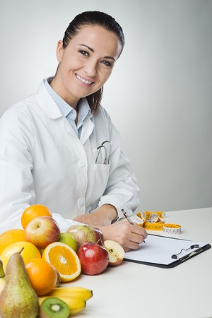 A female doctor sitting at a table with fruit.