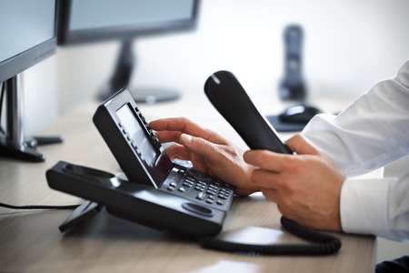 A man is using a telephone in his office.