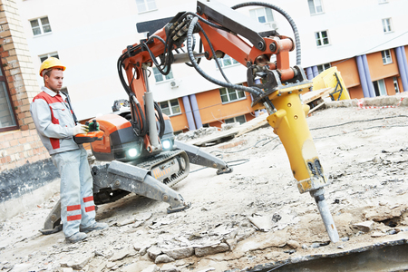 A construction worker is using a machine to dig a hole in the ground.