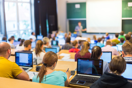 A group of people sitting at desks with laptops in front of them.